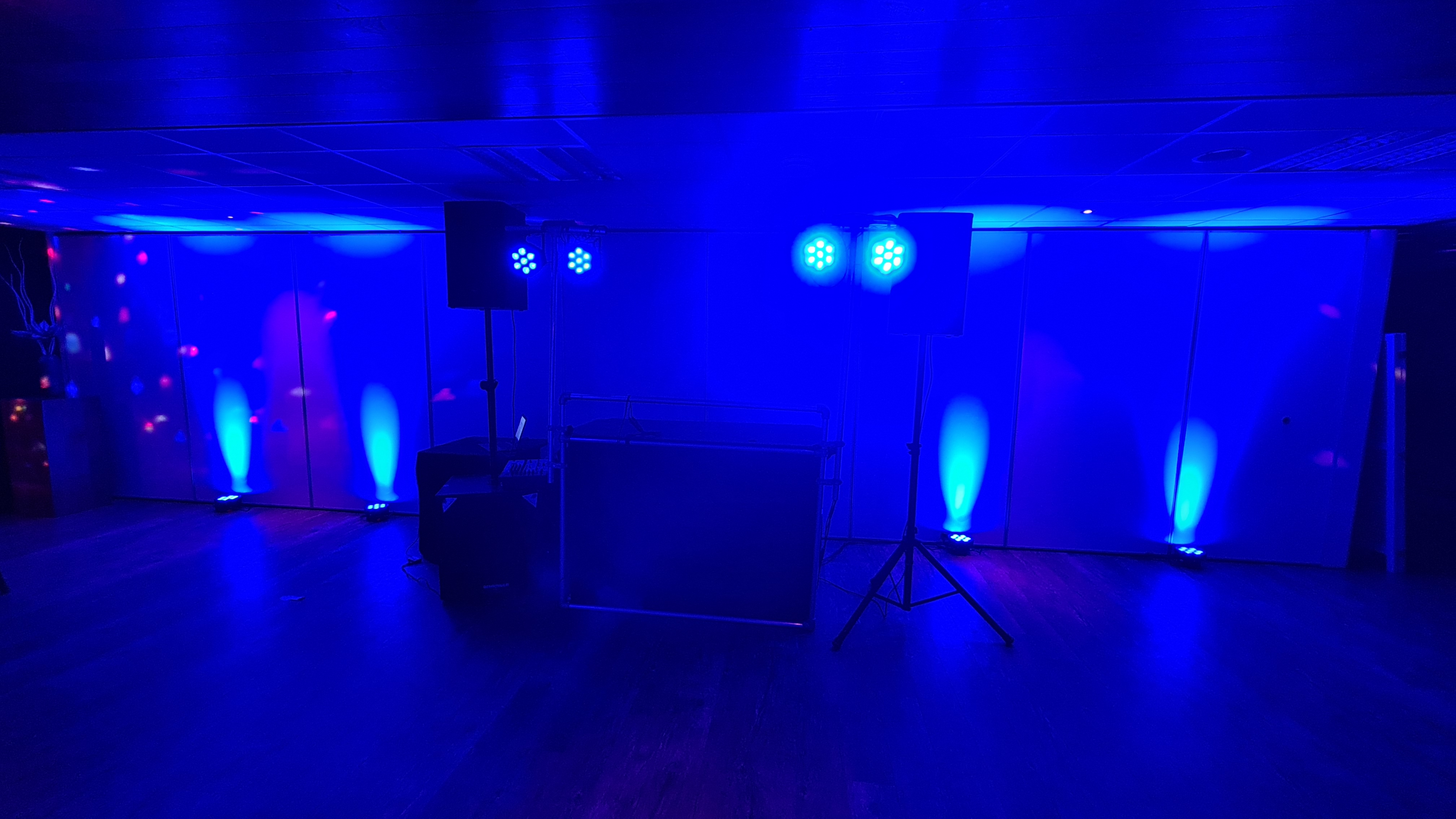 Blauwe uplighting en DJ opstelling tijdens een feestavond